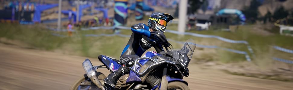 Motociclista in tenuta da guida blu che esegue una curva su una pista sterrata, creando una nuvola di polvere mentre si inclina sulla curva.